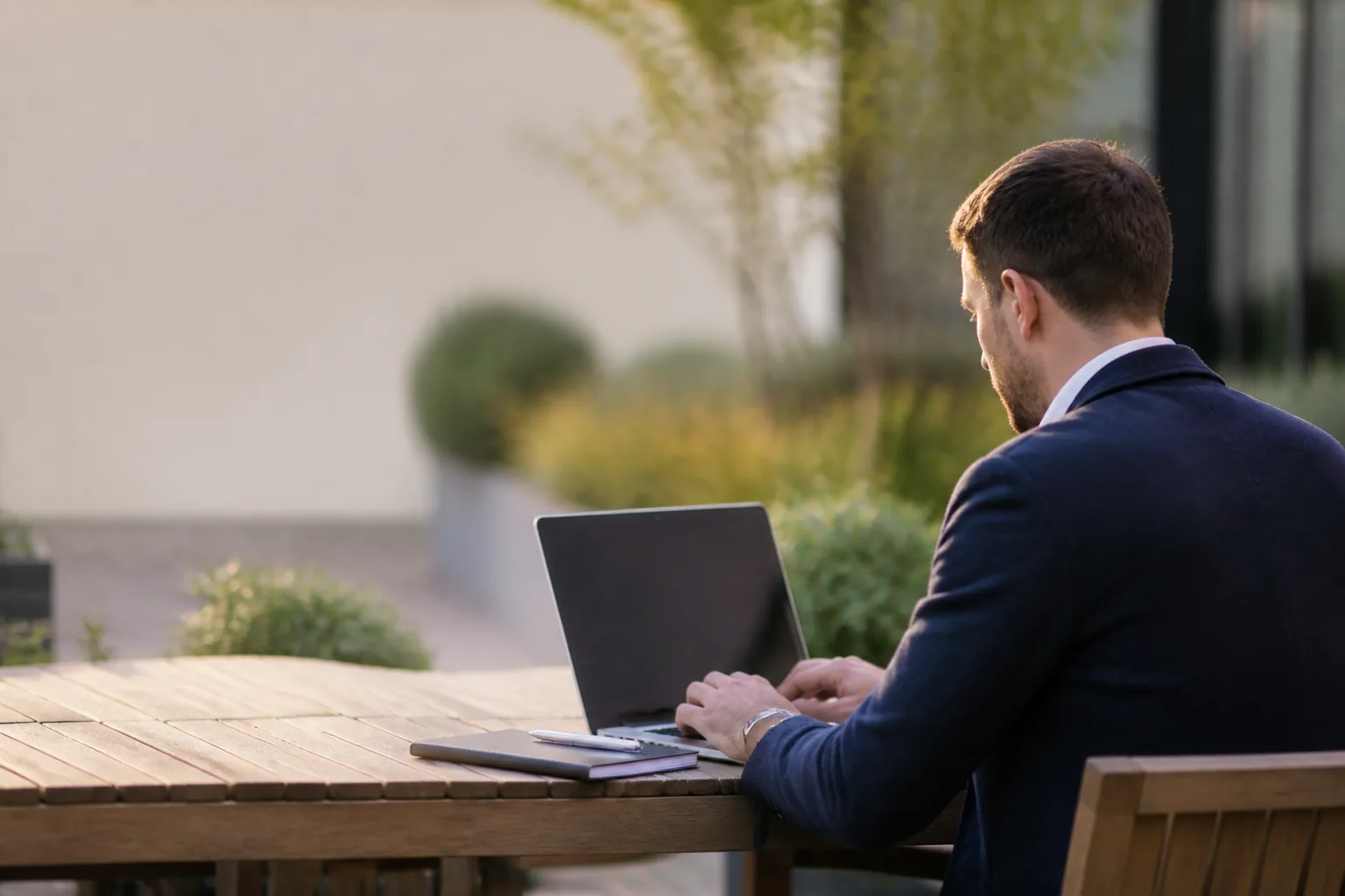 Illustrative business adviser reviewing work on a laptop at an outdoor office table